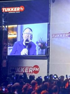 Bezoekers van de Donders Dikke Tent Party kijken naar een live-interview op het grote scherm.